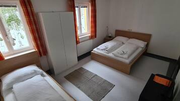Un dormitorio con dos camas, un armario, un radiador y una ventana con cortinas.