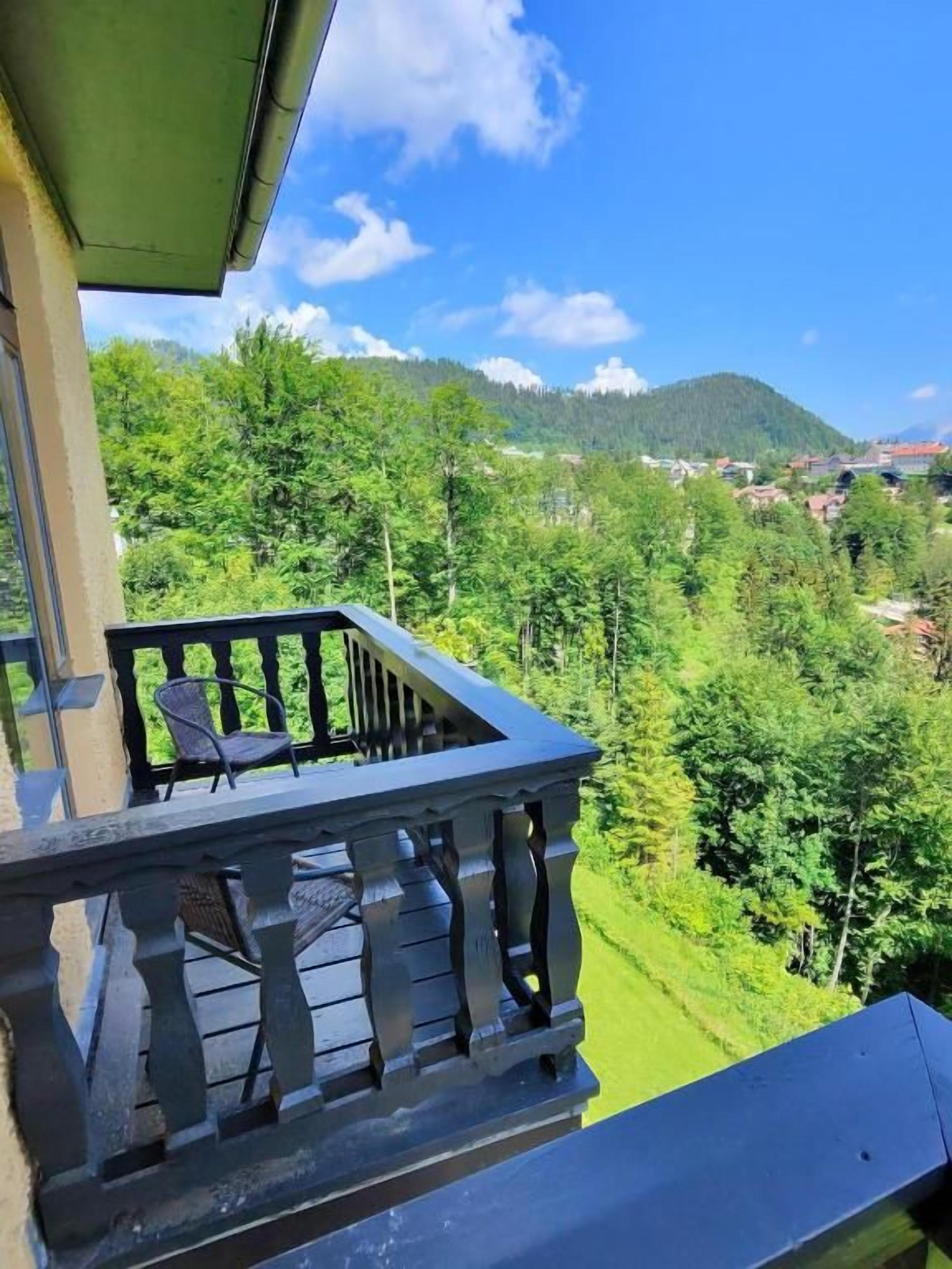 Un balcon offrant une vue sur une colline boisée et une montagne lointaine.