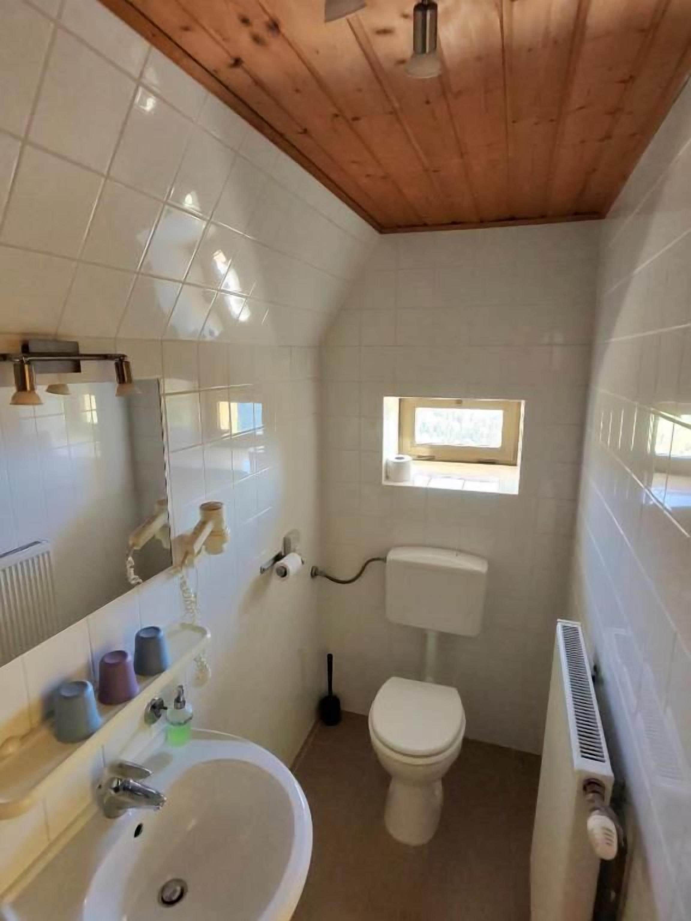 Un baño pequeño con lavamanos, inodoro y una ventana.