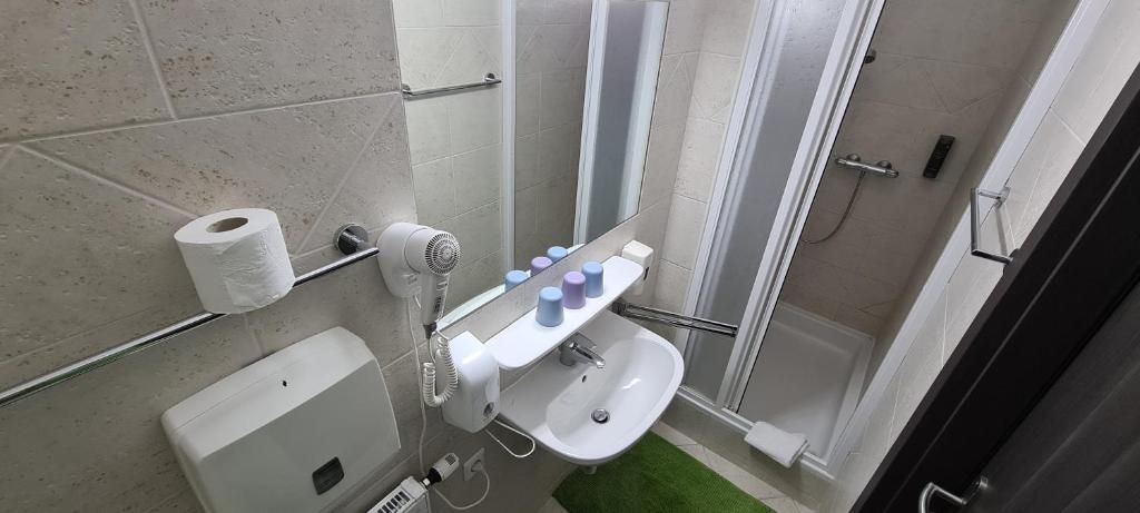 Een badkamer met toilet, wastafel, spiegel, handdoekhouder en douche.