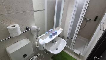 Een badkamer met toilet, wastafel, spiegel, handdoekhouder en douche.
