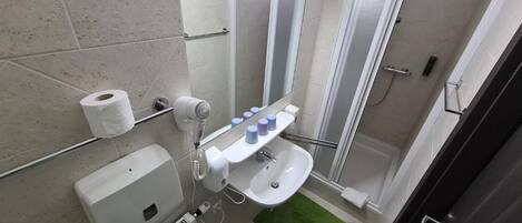 A bathroom with a toilet, a sink, a mirror, a towel rack, and a shower area.