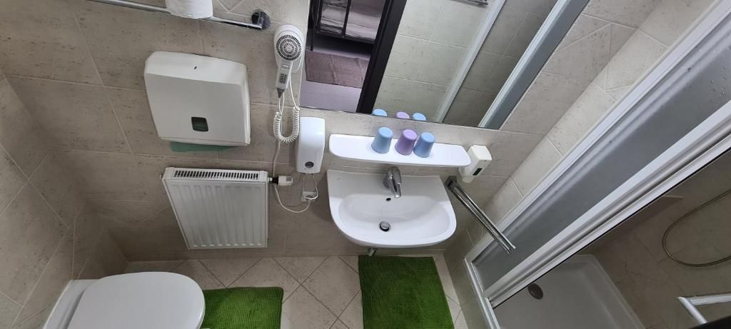 Une salle de bain équipée de toilettes, d’un lavabo, d’un sèche-mains et d’un miroir.