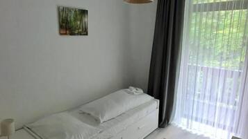 Un dormitorio minimalista con una cama individual, mesita de noche y una lámpara colgante.