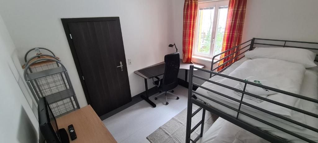Un dormitorio con literas, un escritorio con silla, un armario y una ventana con cortinas.