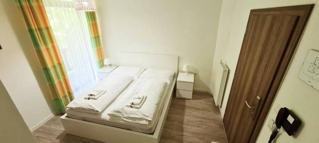 Une chambre d’hôtel avec un lit, des tables de chevet, une porte en bois et un téléphone.