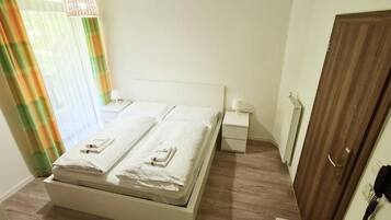 Une chambre d’hôtel avec un lit, des tables de chevet, une porte en bois et un téléphone.