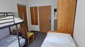 Un dormitorio con literas, una cama individual, un armario de madera y un radiador.