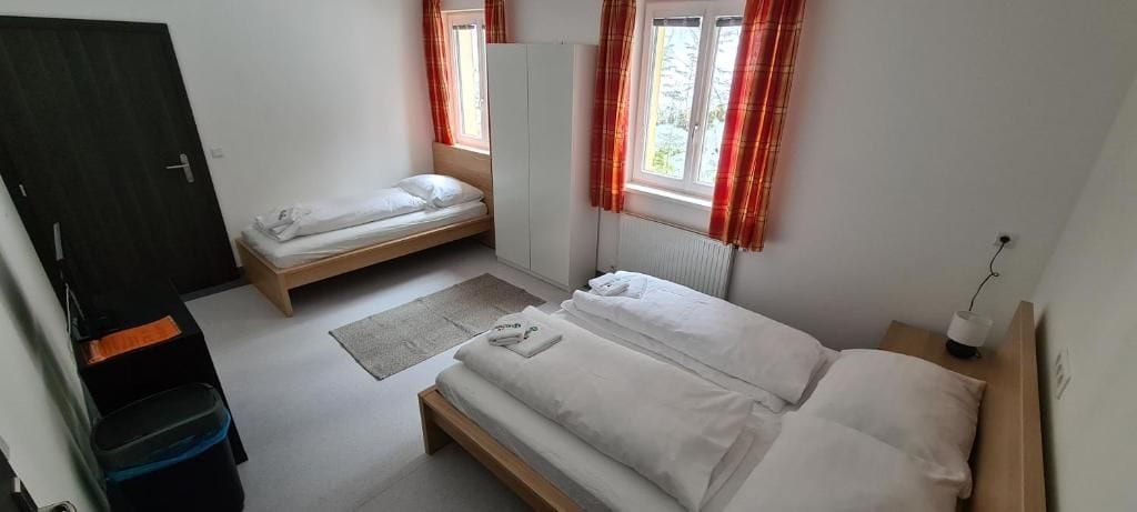 Ein Schlafzimmer mit zwei Einzelbetten, einem Kleiderschrank, einem Heizkörper und einem Fenster mit Vorhängen.