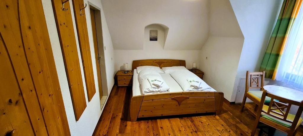 Un dormitorio con una cama de madera, una mesita de noche pequeña, una silla y una ventana con cortinas.