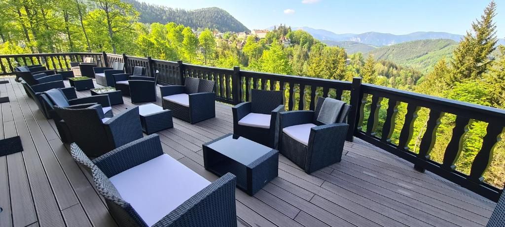 A deck with wicker furniture and a view of a mountainous landscape.