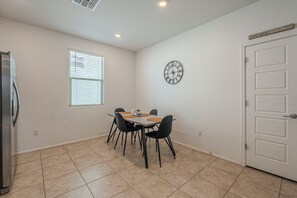 A dining area with a table and chairs, a clock on the wall, and a door with a sign above it. - Cozy 3BR Home in Tucson - Spacious Backyard + Great Location (Tucson)