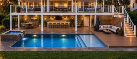 A two-story house with a swimming pool, outdoor seating, and a well-lit patio area.