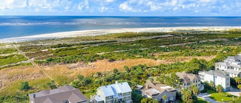 A coastal residential area with houses, a beach, and a clear sky.