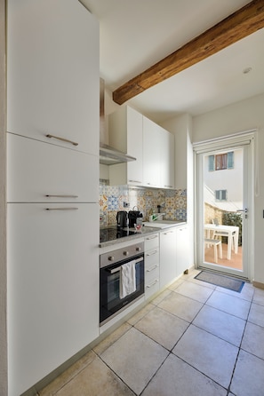 A modern kitchen with white cabinetry, a built-in oven, and a tiled backsplash. - San Niccolò Luxury Apartment (Firenze)