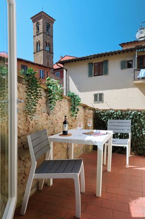An outdoor patio with a table, two chairs, a bottle of wine, and two wine glasses. - San Niccolò Luxury Apartment (Firenze)