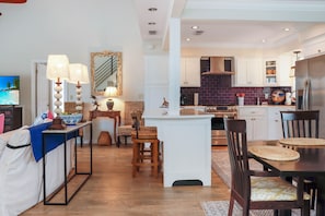 A modern kitchen with white cabinetry, a built-in stove, and a stainless steel refrigerator. - Boardwalk Bungalow (Port St. Joe)