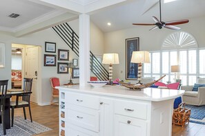 A spacious living area with a central island, a staircase, and a ceiling fan. - Boardwalk Bungalow (Port St. Joe)