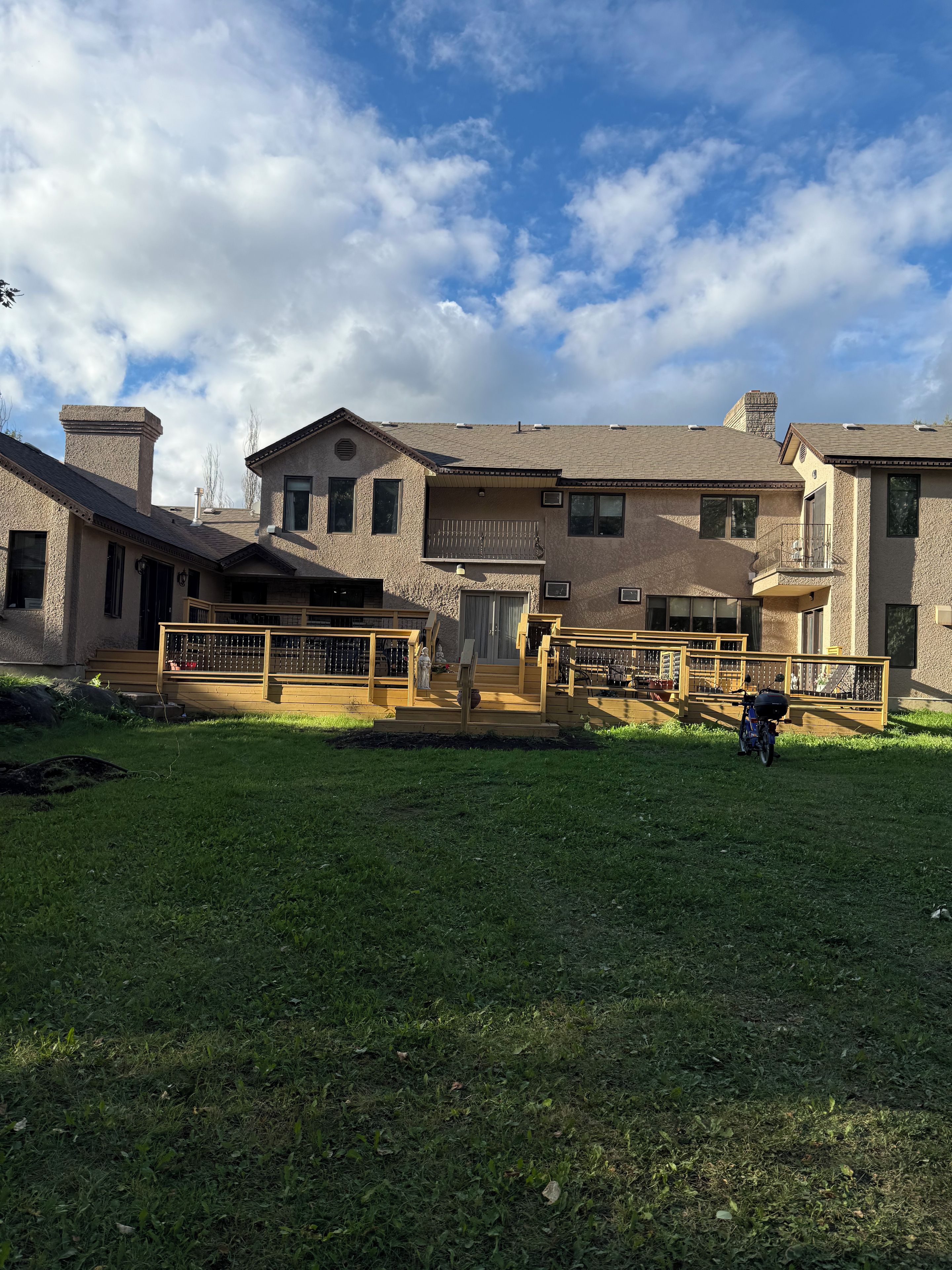 A residential property with a spacious backyard, a covered patio area, and a two-story building with multiple windows and a chimney.