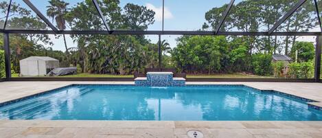 Una piscina con borde de azulejos, rodeada por una zona techada con estructura metálica.