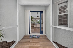 A narrow hallway with a wooden floor leading to a room with a blue door. - Imperial Retreat | Family Friendly Pool Home (Bonita Springs)