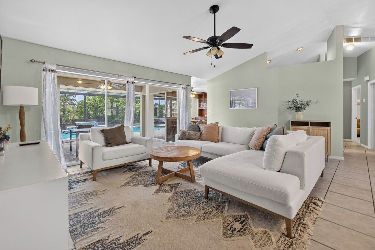 A spacious living room with a ceiling fan, a large window, and a view of the outdoors.