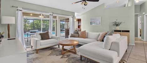 A spacious living room with a ceiling fan, a large window, and a view of the outdoors.