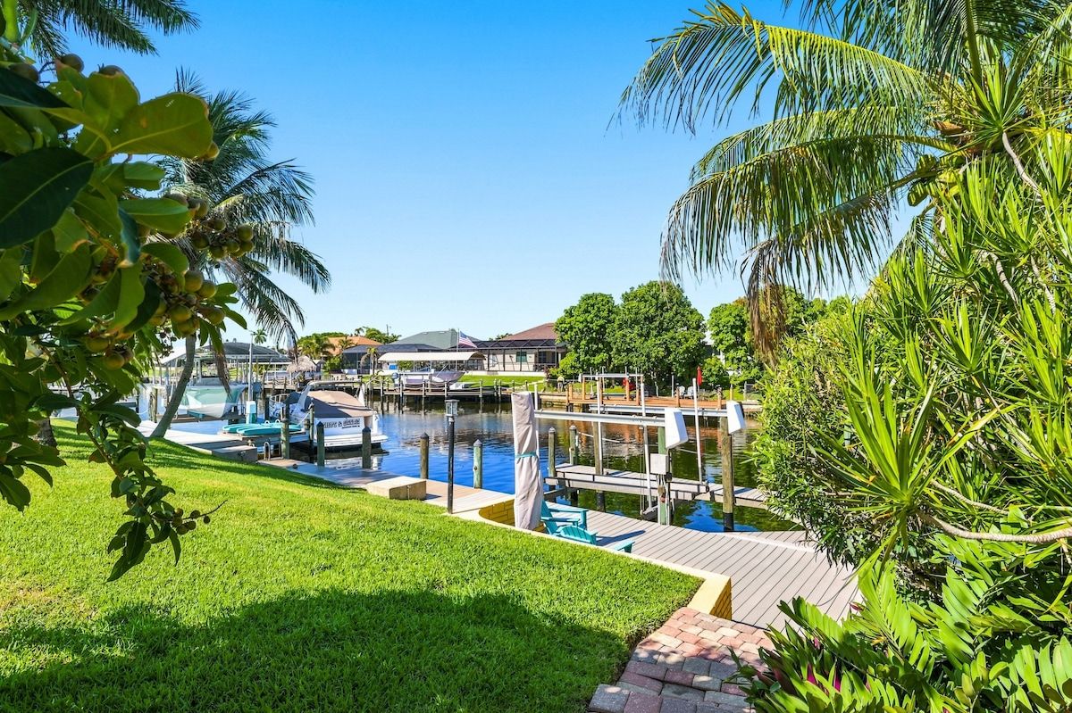 A marina with boats docked, surrounded by lush greenery and palm trees.