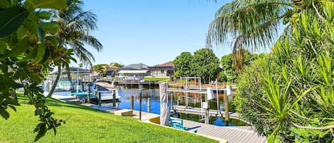 A marina with boats docked, surrounded by lush greenery and palm trees.
