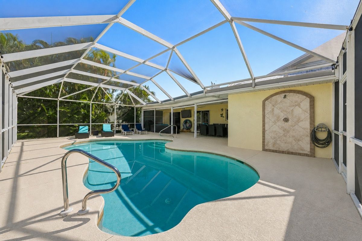 Ein überdachter Swimmingpool mit Glasdach, umgeben von Liegestühlen und einer Sonnenliege.