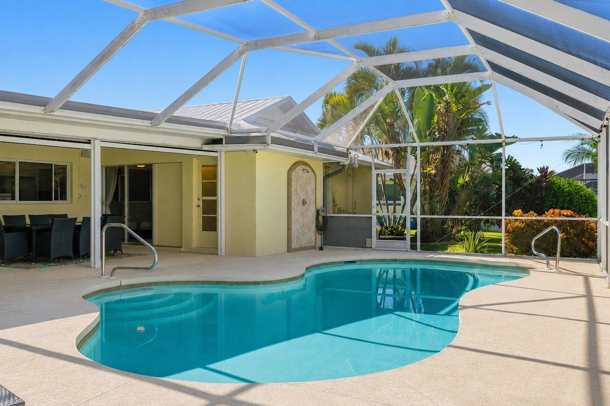 A swimming pool with a covered area, a door, and a chair outside.