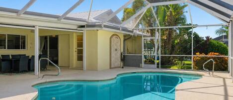 A swimming pool with a covered area, a door, and a chair outside.