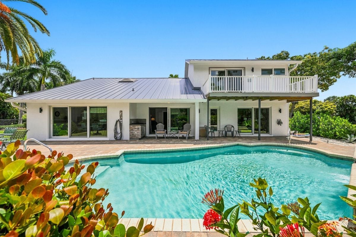 A two-story house with a swimming pool, large windows, and a balcony.