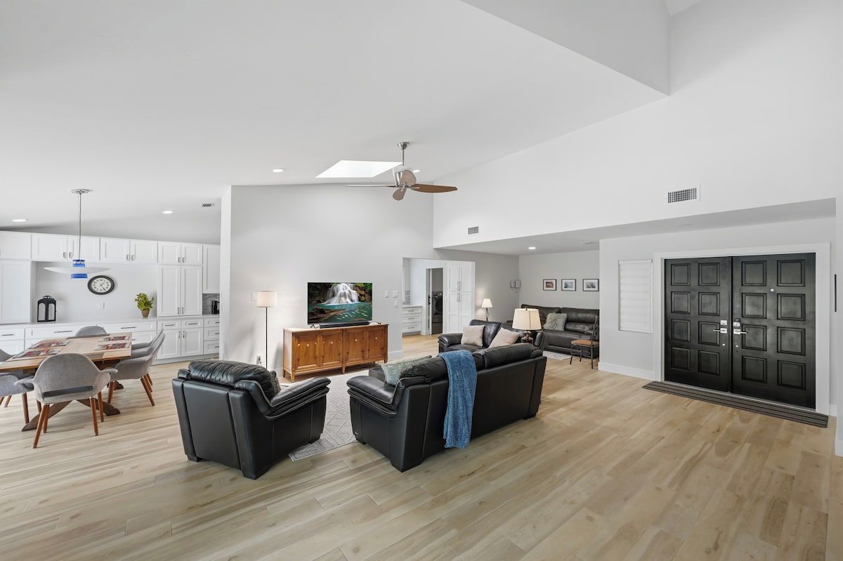 A spacious living area with a dining table, two sofas, a TV, and a fireplace.
