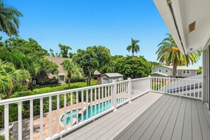 A balcony with a view of a swimming pool and surrounding greenery. - The Palms at McGregor | Luxury 4BR Pool Home (Fort Myers)