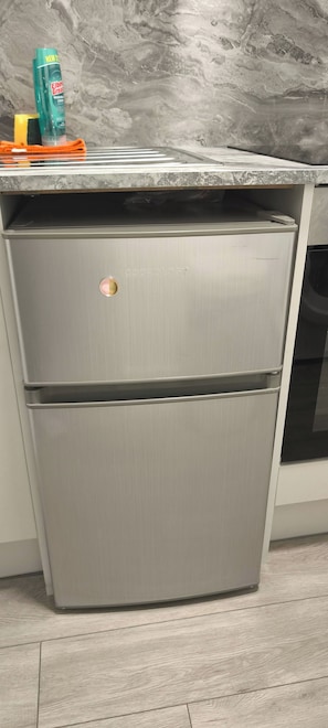 Ein Edelstahl-Kühlschrank mit zwei Türen in einer Küche mit Marmorarbeitsplatte.