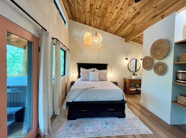 A bedroom with a large bed, wooden ceiling, and a view through a glass door. - Tree Loft: Your romantic treetop escape near Hot Springs. (Bismarck)