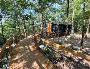 A wooden bridge leading to a rustic cabin in a forested area. - Tree Loft: Your romantic treetop escape near Hot Springs. (Bismarck)
