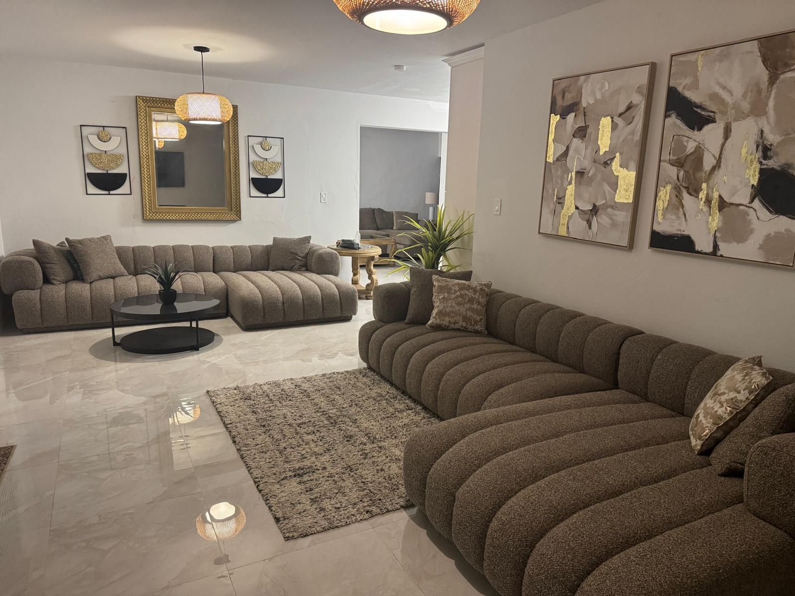 A modern living room with a sectional sofa, a round coffee table, and abstract wall art.