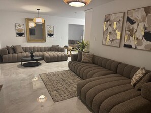A modern living room with a sectional sofa, a round coffee table, and abstract wall art.