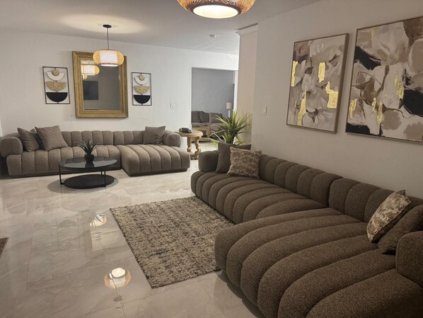 A modern living room with a sectional sofa, a round coffee table, and abstract wall art.