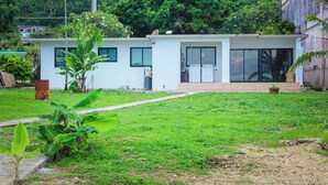A residential building with a front yard, a small garden, and a paved pathway leading to the entrance. - Beautiful Beach house, Sandy white beaches, and sunset views. Must see! (Asan)