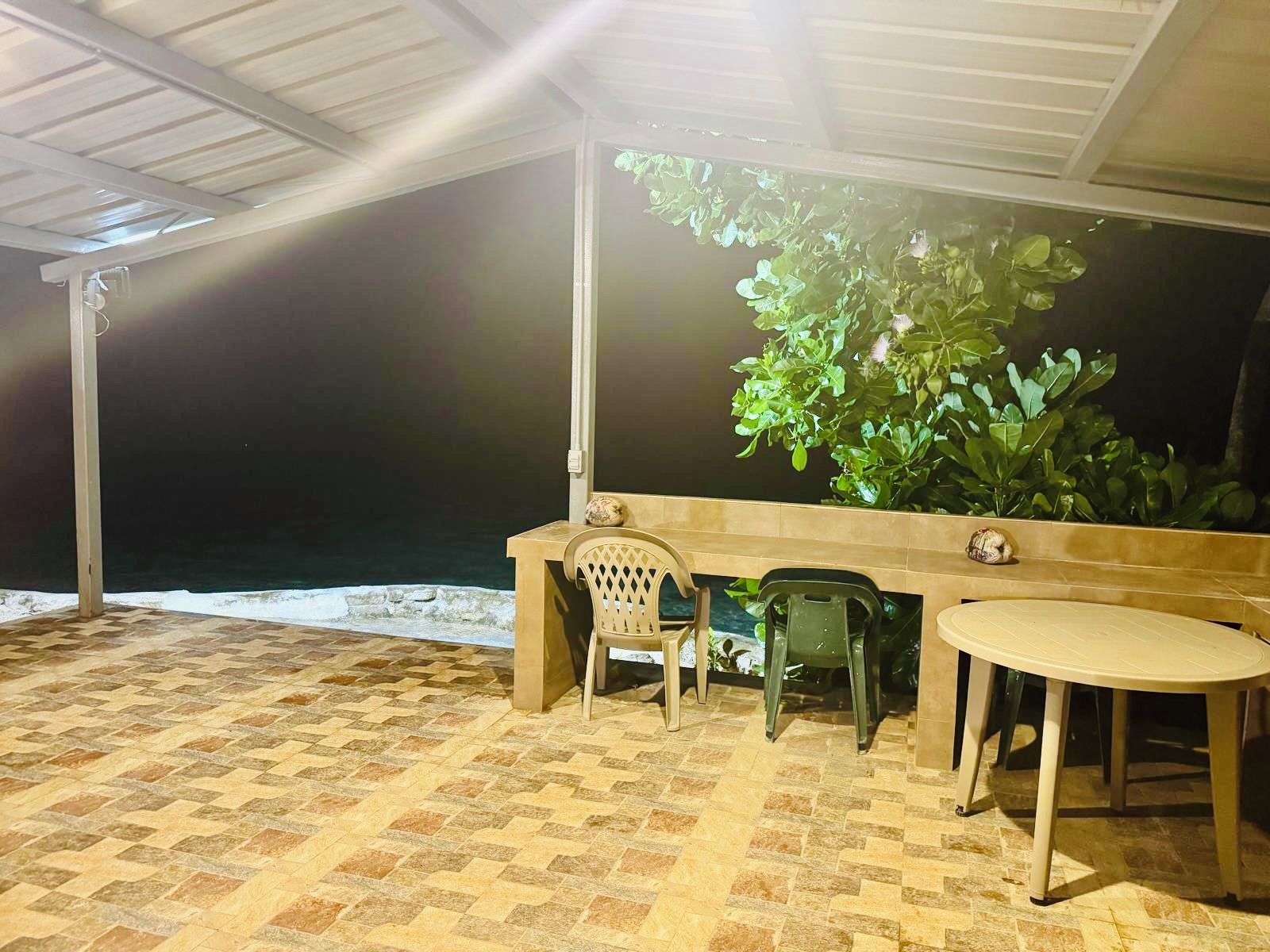 Un espace extérieur aménagé avec une table et des chaises, une plante en pot et un sol carrelé.