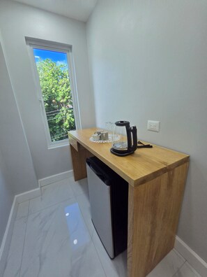 A compact kitchen with a built-in dishwasher, a coffee maker, and a window with a view of greenery.