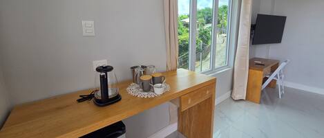 Cocina limpia y moderna con encimera de madera, cafetera y ventana con vistas a zonas verdes.