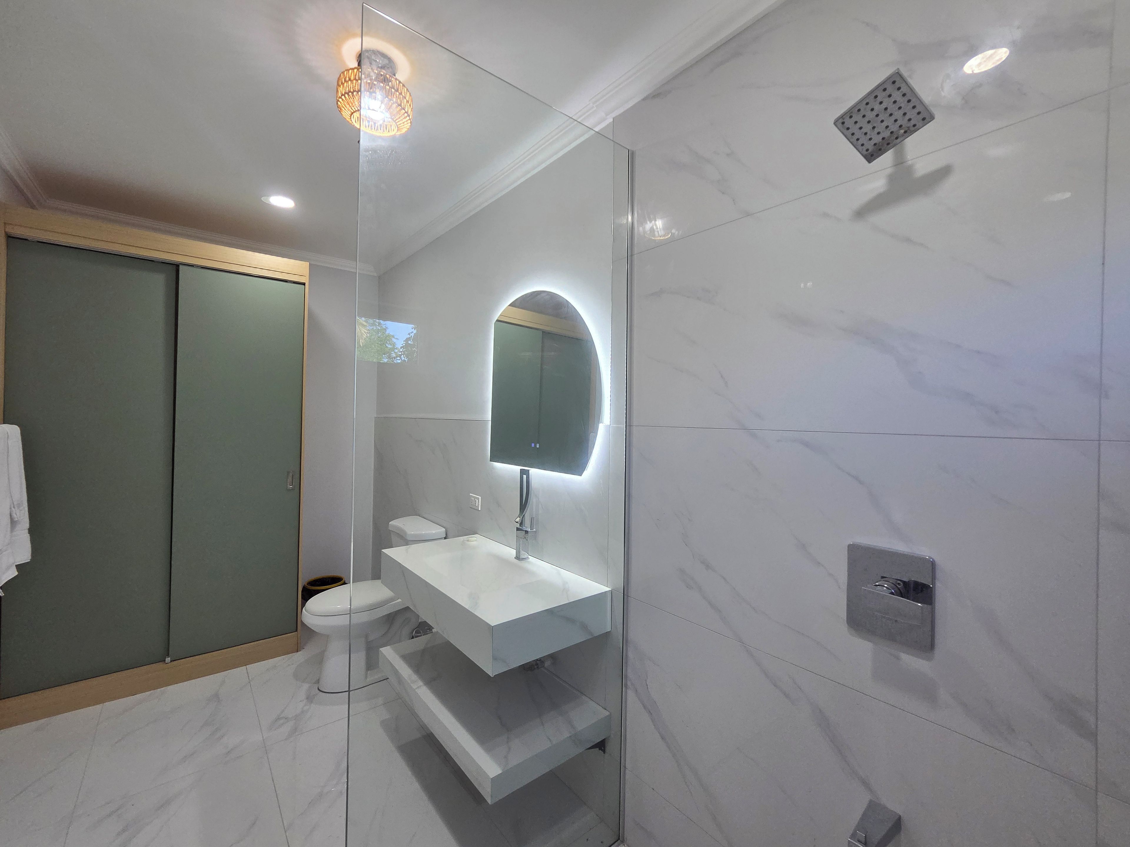 Ein modernes Badezimmer mit einer Duschkabine aus Glas, einem weißen Waschbecken und einer Toilette.