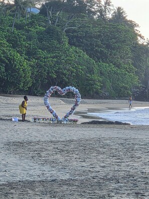 A beach with a heart-shaped floral arrangement and a person standing nearby.