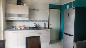 A compact kitchen with white cabinets, a gas stove, and a refrigerator.