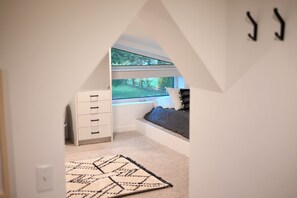Un dormitorio con literas, un escritorio y una ventana con vista a follaje.