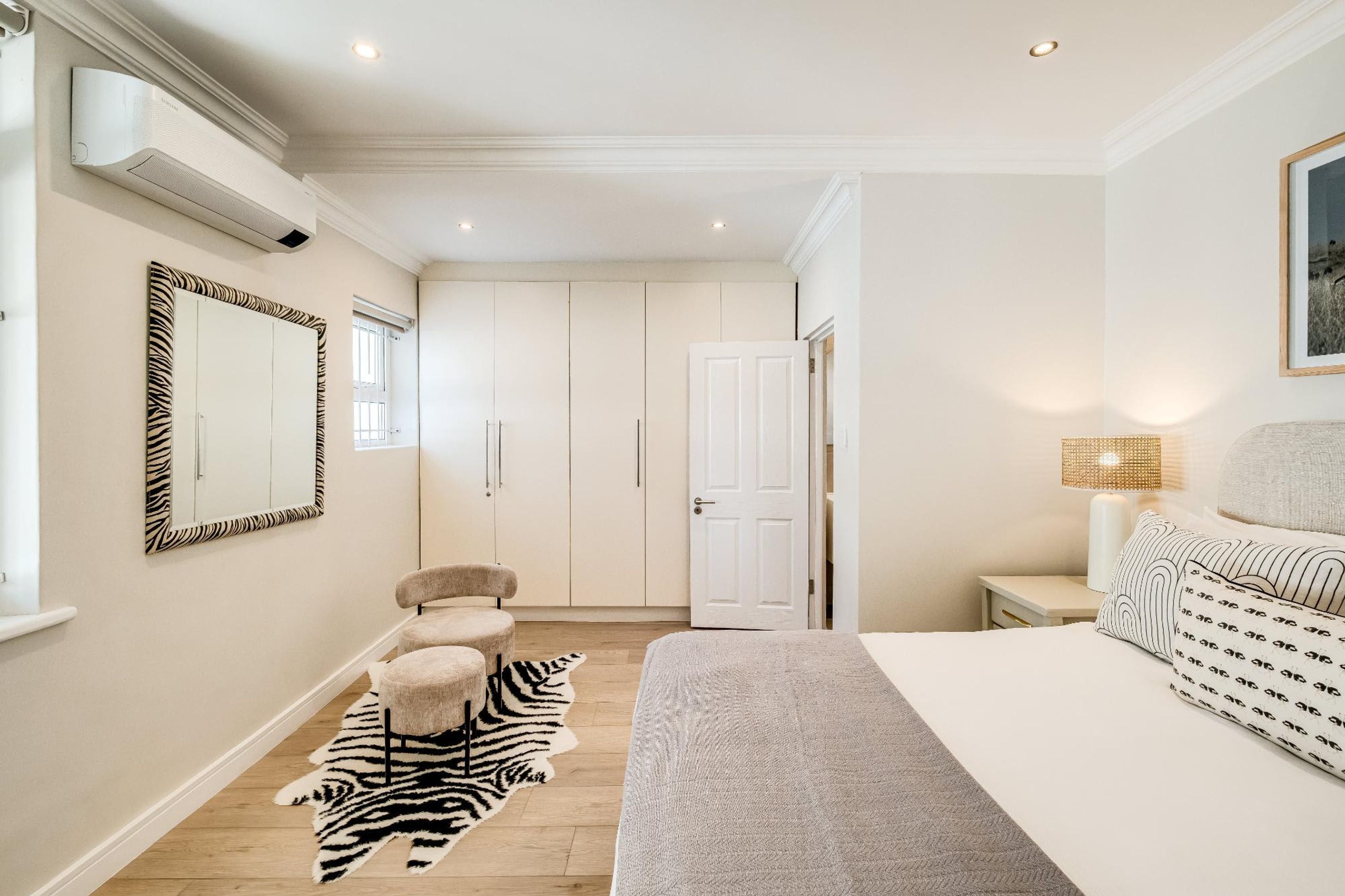 Une chambre à coucher avec un lit, un tapis à motifs zébrés, une chaise, une table de chevet, une lampe et une porte.